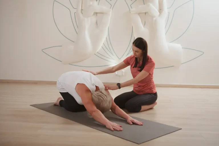 elderly-woman-doing-childs-pose-asana-yoga-class-with-personal-trainer
